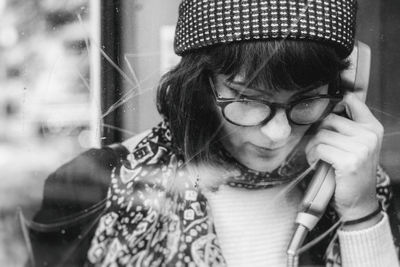 Close-up of young woman talking in telephone booth