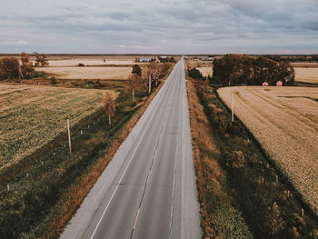 Empty road amidst field against sky