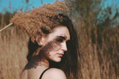 Side view of thoughtful young woman standing by plants