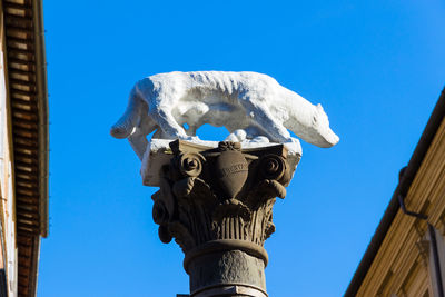 Low angle view of statue against building against clear blue sky