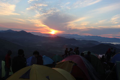 People on mountains against sky during sunset