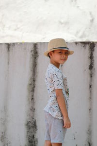 Portrait of cute boy in hat standing by wall