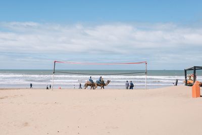 People at beach against cloudy sky