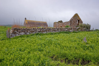 Old ruins of building on field against sky