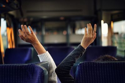 Cropped image of people with arms raised in bus