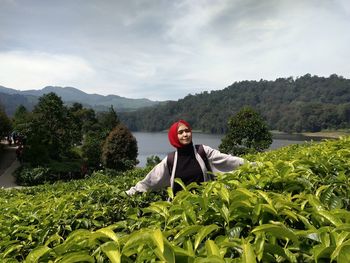 Portrait of young woman against plants and trees