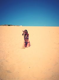 People on beach against clear blue sky