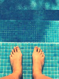 Low section of person standing at poolside on sunny day