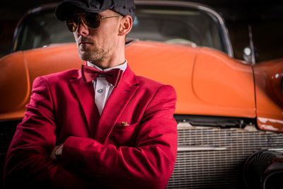 Man standing against vintage orange car