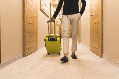 Low section of man pulling luggage in hotel corridor