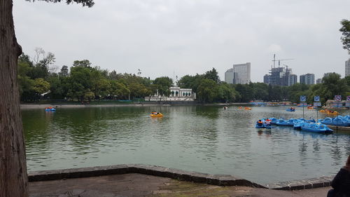 Boats moored in lake against sky in city