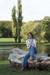 Young woman sitting on rock against lake