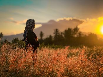 Side view of woman on field during sunset