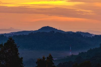 Scenic view of silhouette mountains against orange sky