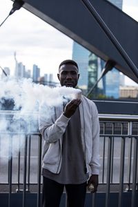 Portrait of young man standing against railing