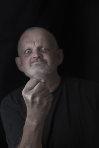 Portrait of man showing fist against black background