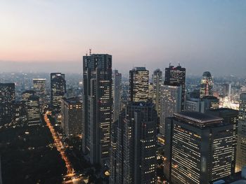 Illuminated cityscape against sky during sunset