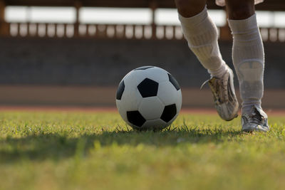 Low section of person playing soccer ball on grass