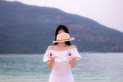 Young woman levitating hat while standing at beach