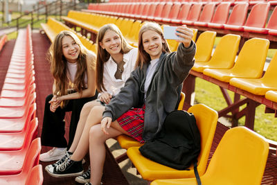 Three charming friends take selfies on their phone at the school stadium. the concept of friendship. 
