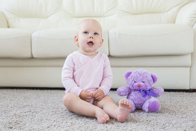 Cute baby girl sitting on sofa at home