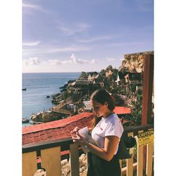 Boy standing by sea against sky