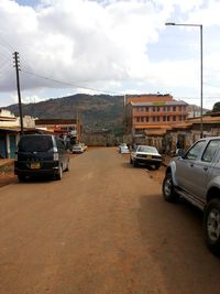 Cars parked on road against cloudy sky