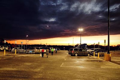 Cars parked on road against cloudy sky