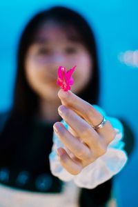 Close-up of woman holding flower gift against blue background