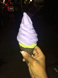 Close-up of hand holding ice cream cone at night