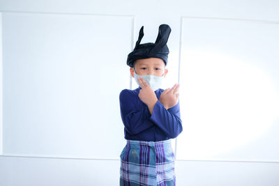 Portrait of boy standing against wall