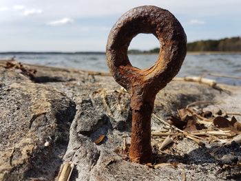 Close-up of rusty metal on beach against sky