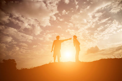 Silhouette friends standing against sky during sunset