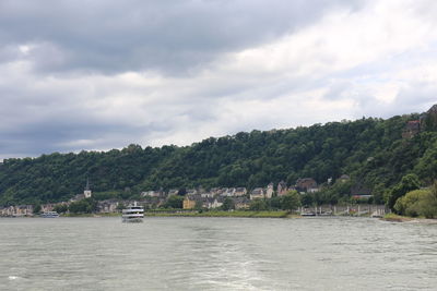 Scenic view of river by trees and buildings against sky