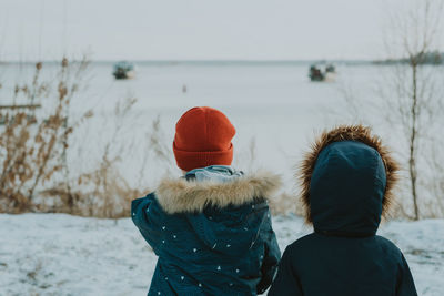 Rear view of people walking in snow during winter