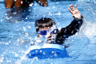 Close-up of boy with kickboard swimming in pool