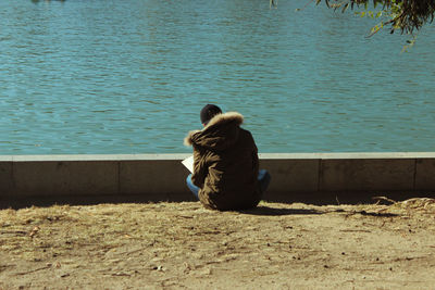 Rear view of woman sitting by lake