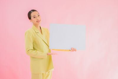 Woman standing against pink background