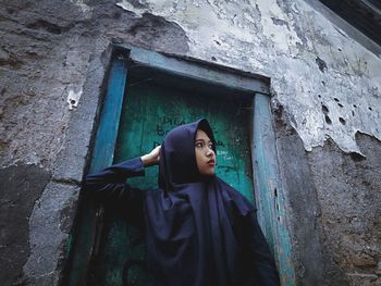 Portrait of woman standing against wall