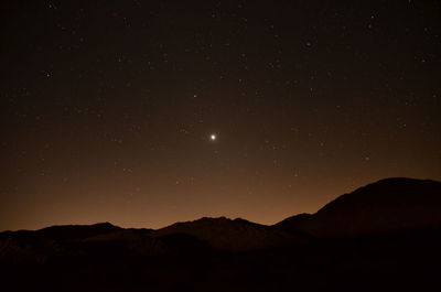 Scenic view of silhouette mountains against sky at night