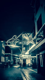 Illuminated street amidst buildings in city at night