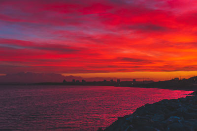 Scenic view of sea against dramatic sky during sunset