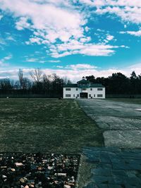 Scenic view of field by buildings against sky