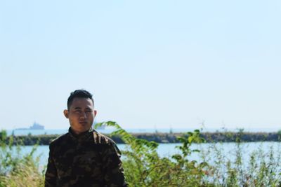 Portrait of young man standing against clear sky