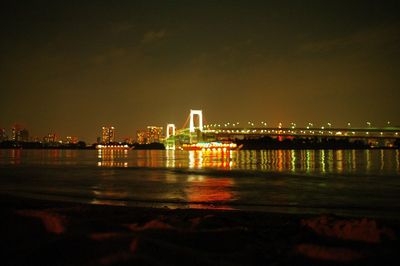 Illuminated bridge over river at night