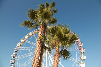 Low angle view of ferris wheel against clear blue sky