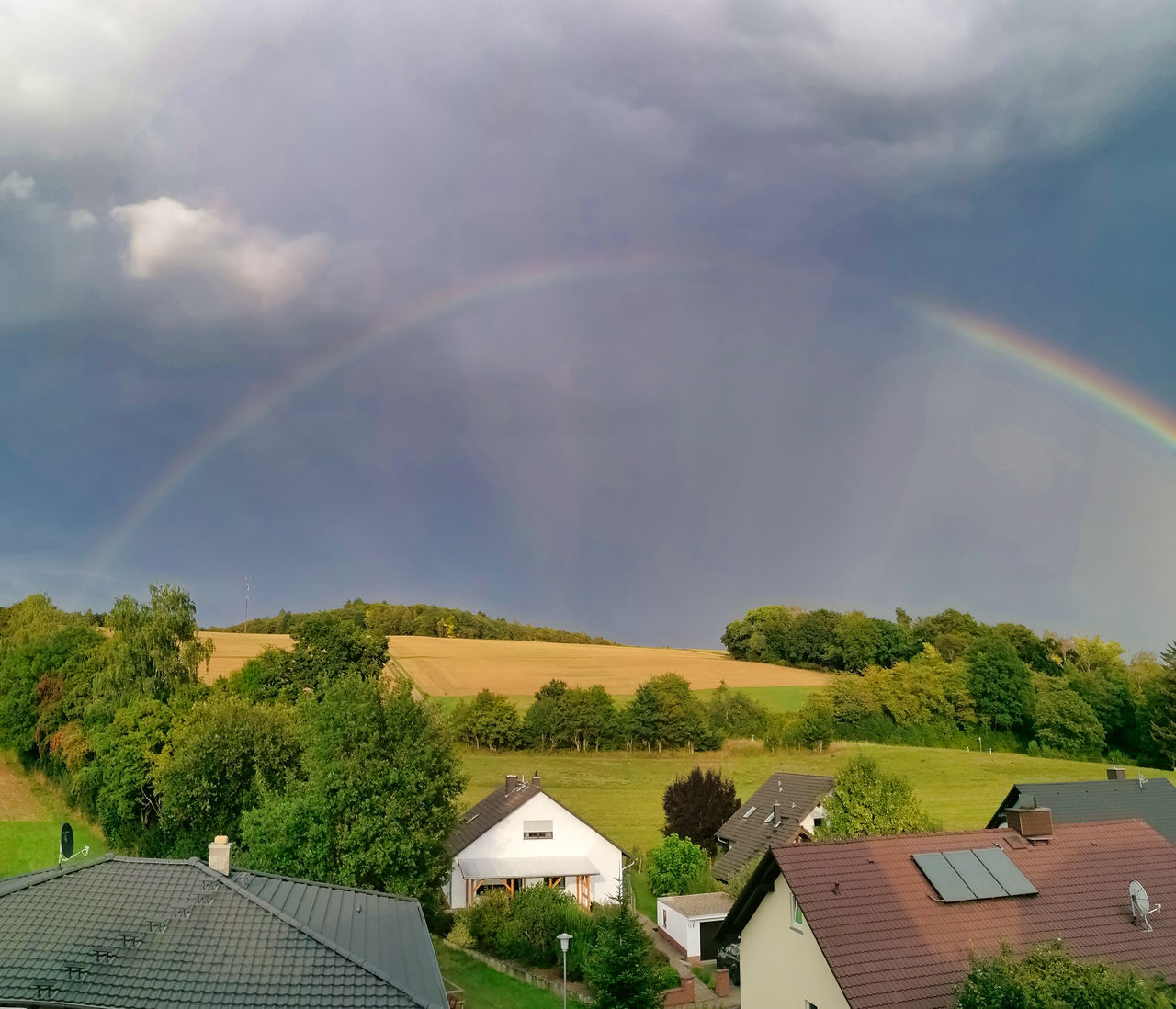 SCENIC VIEW OF RAINBOW OVER TREES AND BUILDINGS