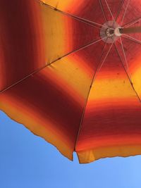 Low angle view of orange umbrellas against sky