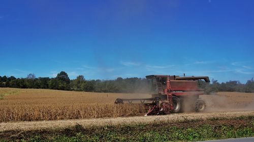 Tractor on agricultural field against clear blue sky