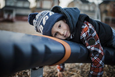 Portrait of cute boy lying on outdoor play equipment at playground